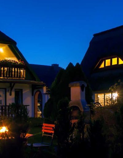 Ferienwohnungen am Abend mit beleuchtetem Garten auf dem Wassergrundstück