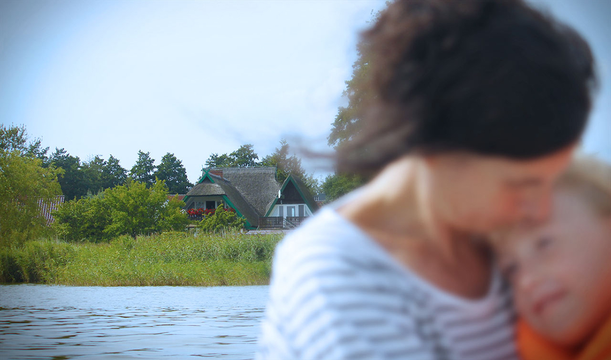 Bootstour auf dem Barther Strom mit Hausansicht unter Reet vom Wasser aus.